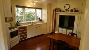 Une cuisine avec une fenêtre, un évier, une cuisinière et une table à manger avec des chaises.
