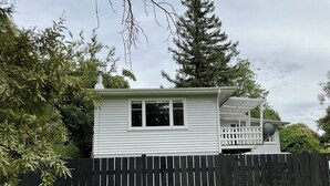 Une maison blanche d’un seul étage, dotée d’une cour clôturée, d’un balcon et d’une antenne parabolique.