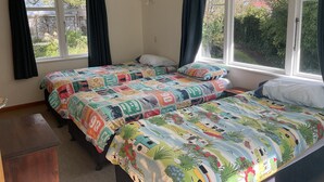 Une chambre avec deux lits, de grandes fenêtres et une vue sur la verdure.