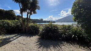Un sendero de grava que lleva a un lago con palmeras y vegetación densa.