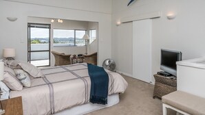 Un'ampia camera da letto con un grande letto, una televisione e vista sull'esterno attraverso una finestra.