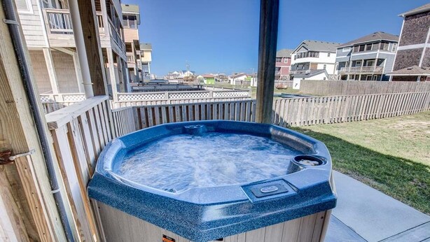 Een bubbelbad op een houten terras met uitzicht op woongebouwen op de achtergrond.