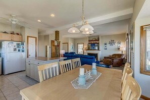 A modern kitchen with a dining area, a living room with a fireplace, and a ceiling fan. - Derrycon | Oceanfront | Dog Friendly, Private Pool, Hot Tub | Nags Head (Nags Head)