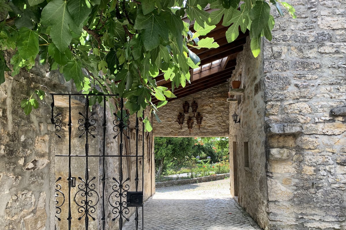 A stone archway with a wrought iron gate leading to a cobblestone path.
