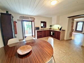 Et moderne køkken med spiseplads, en væg med stenkaldetaljer og udsigt gennem døren.