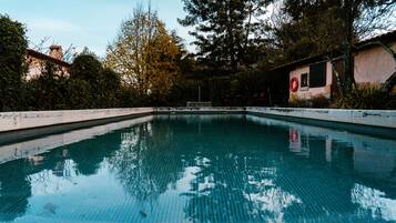 Una piscina al aire libre de temporada, tumbonas