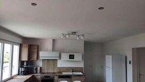 Eine moderne Küche mit Essbereich, Holzschränken, einer eingebauten Mikrowelle und einem weißen Kühlschrank.