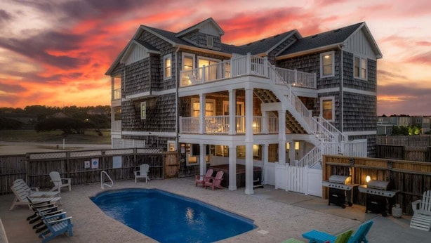 Uma casa de dois andares com piscina, área de estar ao ar livre e escadas que levam ao andar superior.