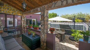 Un patio couvert agrémenté de piliers en pierre, de mobilier d’extérieur et de plantes en pot.