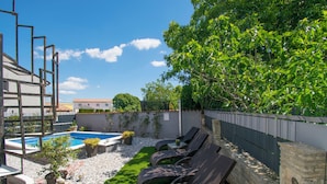 Un espace piscine aménagé sur le toit, avec des chaises longues, une petite piscine et de la verdure tout autour.