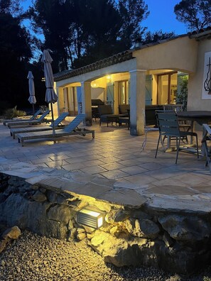 Un espace extérieur aménagé en terrasse, avec des chaises longues, une table et des parasols.