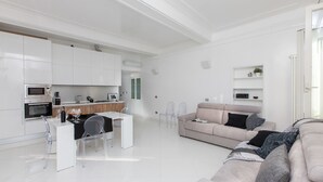 A modern, minimalist living space with a kitchen, dining area, and seating area. - Rental In Rome Piazza Venezia View Luxury Apartments (Rome)
