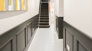 Um corredor com piso estampado, escada e parede decorada com arte abstrata.