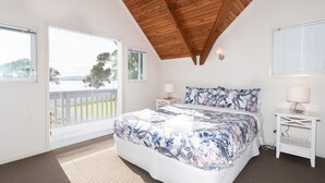 Un dormitorio con una cama grande, techo de madera y vistas al exterior a través de las ventanas.