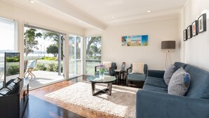 Un salón espacioso con un sofá azul, una mesa de centro de vidrio y vistas a un balcón con mobiliario exterior.