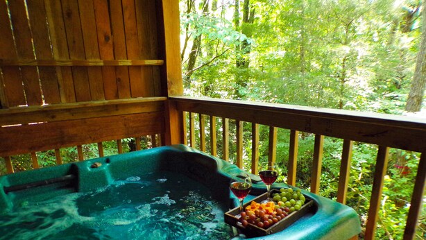 A hot tub with a wooden deck and a view of a forest. - ❤ VERY ROMANTIC CABIN ❤ Near Cades Cove, WIFI, Hot Tub, Jacuzzi, Sauna (Townsend)