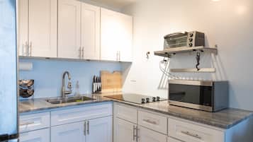 A kitchen with white cabinets, a stainless steel sink, a microwave, and a toaster on a countertop.