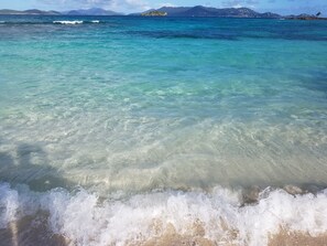 A beach with clear turquoise water and waves. - The Mermaid's Pearl at Sapphire Beach (St. Thomas)