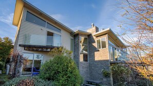Een modern herenhuis met twee verdiepingen, een stenen gevel, grote ramen en een verzorgde tuin.