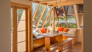 Una habitación acogedora con un banco de madera, una mesa, ventanas amplias y un candelabro.