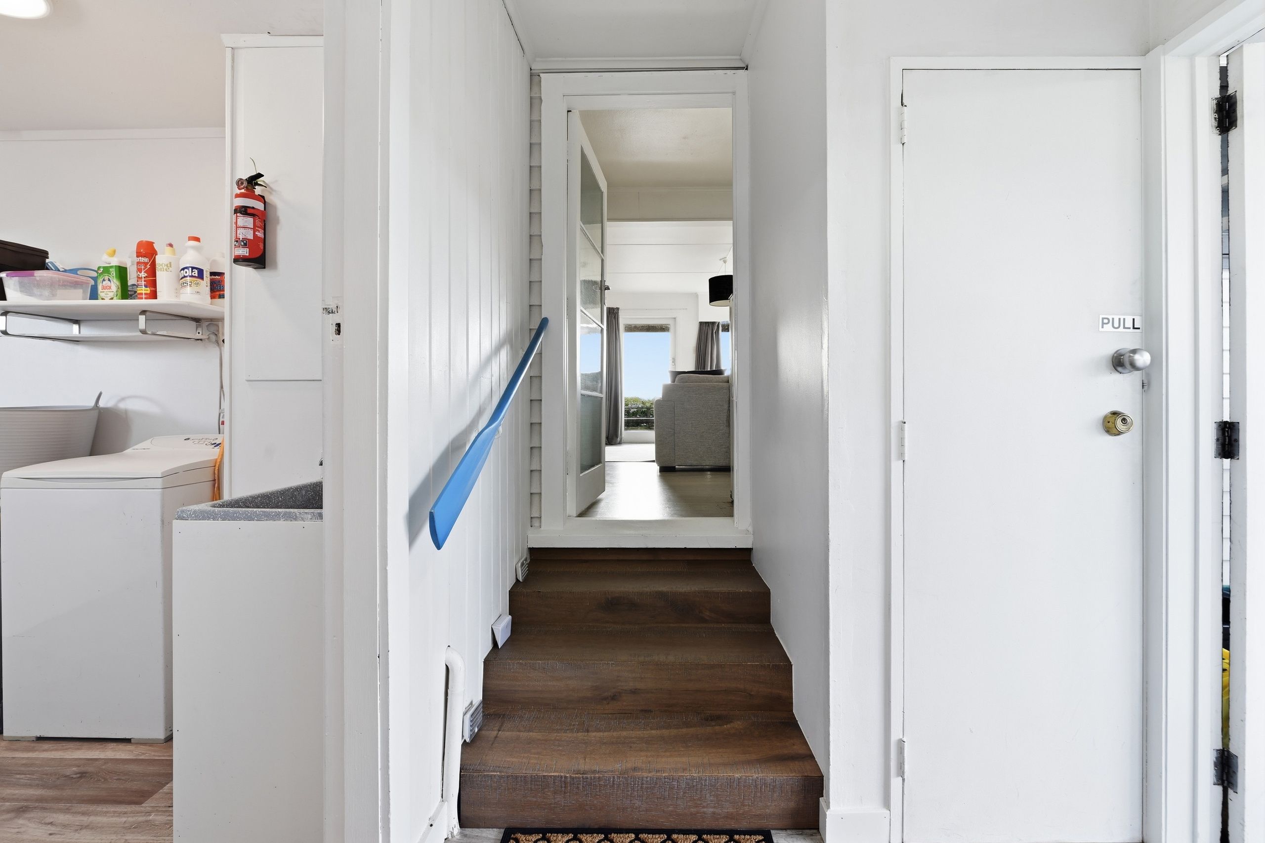 A hallway with a wooden staircase leading to a room with a view.