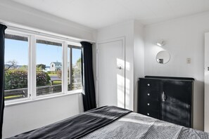 A bedroom with a bed, a wardrobe, a window with curtains, and a wall-mounted light fixture.
