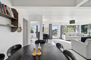 Una sala de estar moderna con una mesa de comedor, sofás y una estantería.