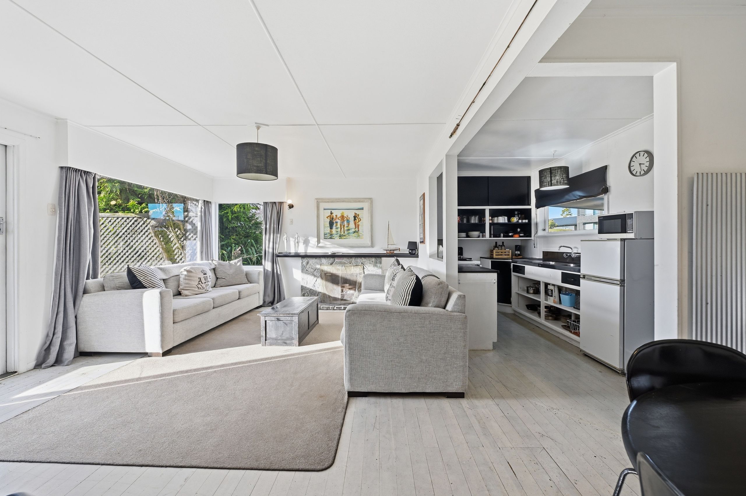 A modern living room with a fireplace, a dining area, and a kitchen with built-in appliances.