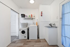 A compact laundry room with a washing machine, dryer, and a shelf with cleaning supplies.