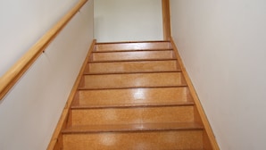 A wooden staircase with a handrail on the left and a wall on the right. - Aqua Views - Kuratau Holiday Home (Kuratau)