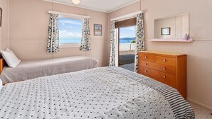 Un dormitorio con dos camas, un aparador y una ventana con cortinas.