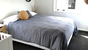 A bedroom with a bed, a nightstand, a window, and a wall-mounted mirror. - The reviews say it all! A blissful bach, & pet friendly! (Mangakino)