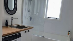A compact bathroom with a sink, mirror, washing machine, and a shower. - The reviews say it all! A blissful bach, & pet friendly! (Mangakino)