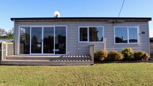 A single-story mobile home with a sliding glass door entrance, a small porch, and a satellite dish on the roof. - The reviews say it all! A blissful bach, & pet friendly! (Mangakino)