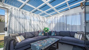 A sunroom with a sectional sofa, a coffee table, and a large window.