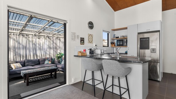 A modern kitchen with a central island, bar stools, and a refrigerator.