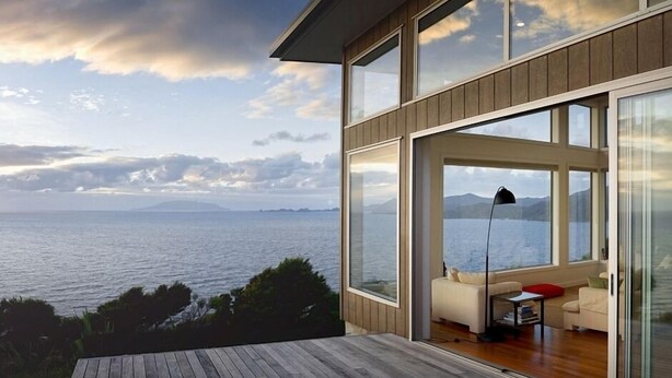 A modern house with large glass windows overlooking a body of water and mountains. - XSPOT Cliff 4WD holiday apartment for two - Spectacular 270° Hauraki Gulf views (Tryphena)