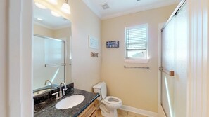 A bathroom with a sink, toilet, and window.