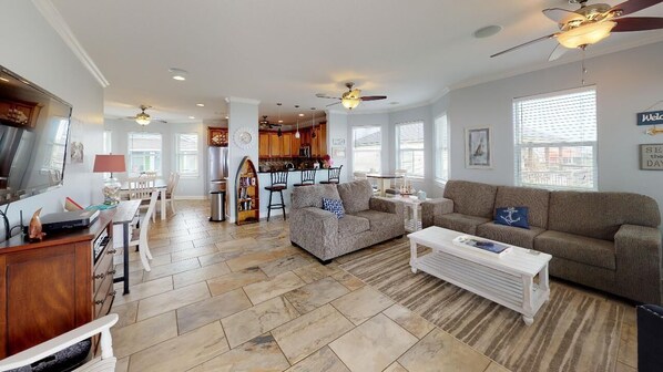 A spacious living area with a dining table, sofas, and a kitchen in the background.