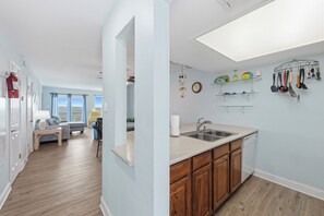 A modern kitchen with wooden cabinets, a built-in dishwasher, and a window overlooking a balcony.