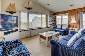 A living room with striped sofas, a coffee table, and a bookshelf.