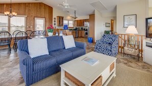 A spacious living room with a striped sofa, a white coffee table, and a patterned armchair. A dining area with a wooden table and chairs is visible in the background. - Near The Edge | 95 ft from the beach | Community Pool | Duck (Duck)