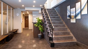 A modern hotel lobby with a staircase, a reception desk, and a clock on the wall. - Hotel Kojan Shinsaibashi (Osaka)