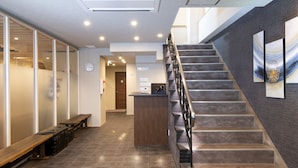 A reception area with a staircase, a reception desk, and a wall-mounted clock. - Hotel Kojan Shinsaibashi (Osaka)