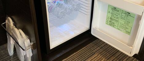 A refrigerator with a freezer compartment containing bottled water and a small compartment with a green label.