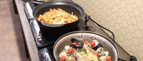 A kitchen with various dishes being cooked on a stove, including seafood and vegetables.