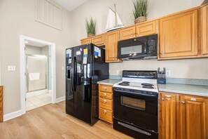 Una cocina con armarios de madera, un refrigerador negro, un microondas y una estufa.