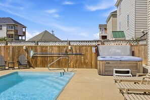 A backyard with a swimming pool, a hot tub, and wooden deck chairs. - Spur of the Moment | 293 ft from the beach | Private Pool, Hot Tub | Kill Devil Hills (Kill Devil Hills)