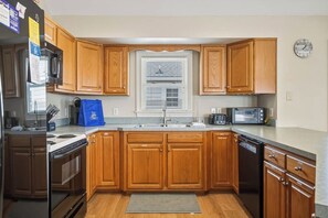 A kitchen with wooden cabinets, a built-in microwave, a stove, and a dishwasher. - Spur of the Moment | 293 ft from the beach | Private Pool, Hot Tub | Kill Devil Hills (Kill Devil Hills)