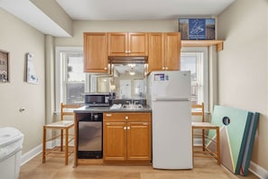 A compact kitchen with wooden cabinets, a white refrigerator, and a microwave.